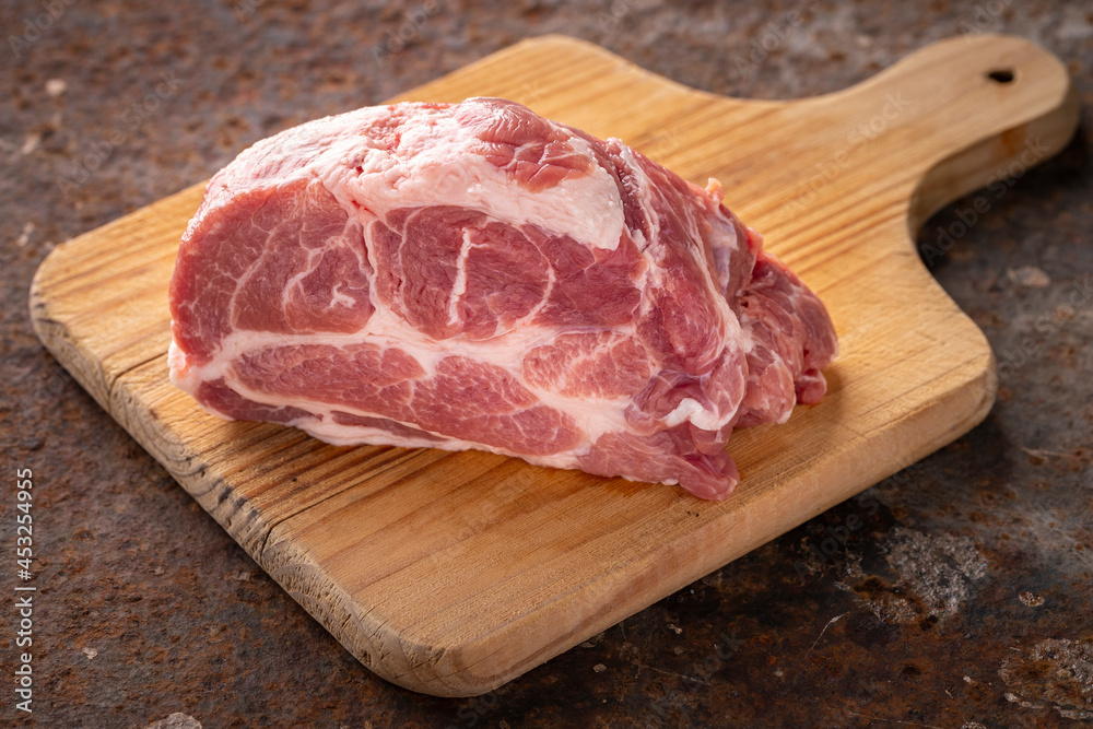 fresh raw pork neck meat fillet in wooden cutting board on rusty texture background, ingredient for chop steak fresh raw pork neck meat fillet in wooden cutting board on rusty texture background, ingredient for chop steak