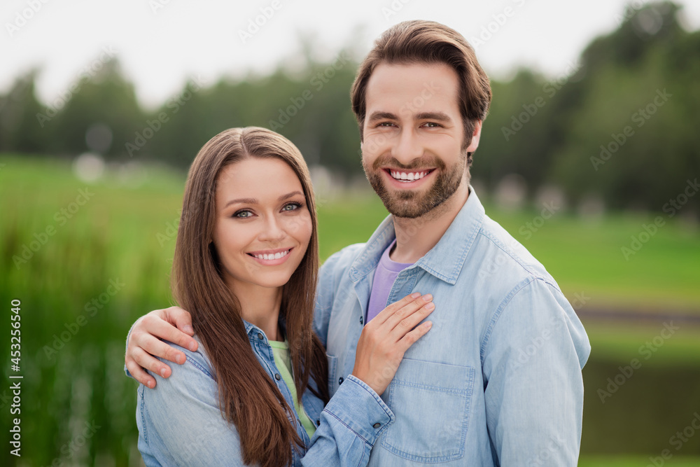 Fototapeta premium Photo portriat young couple smiling embracing walking in green city park wearing jackets