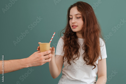 The girl is handed a paper cup with a straw