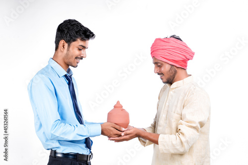 Saving concept : Young indian banker and farmer holding clay piggy bank in hand photo