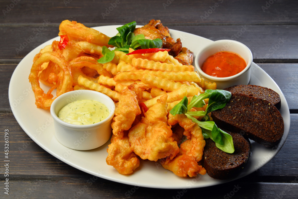 fried snacks Onion rings, chicken wings, bread with sauce on a plate fried snacks Onion rings, chicken wings, bread with sauce on a plate