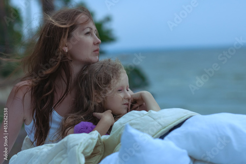 Foto Woman with baby sleep on a bed outdoors by the ocean.