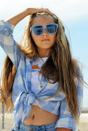 beautiful teenage girl with long hair wearing blue glasses and a plaid shirt portrait