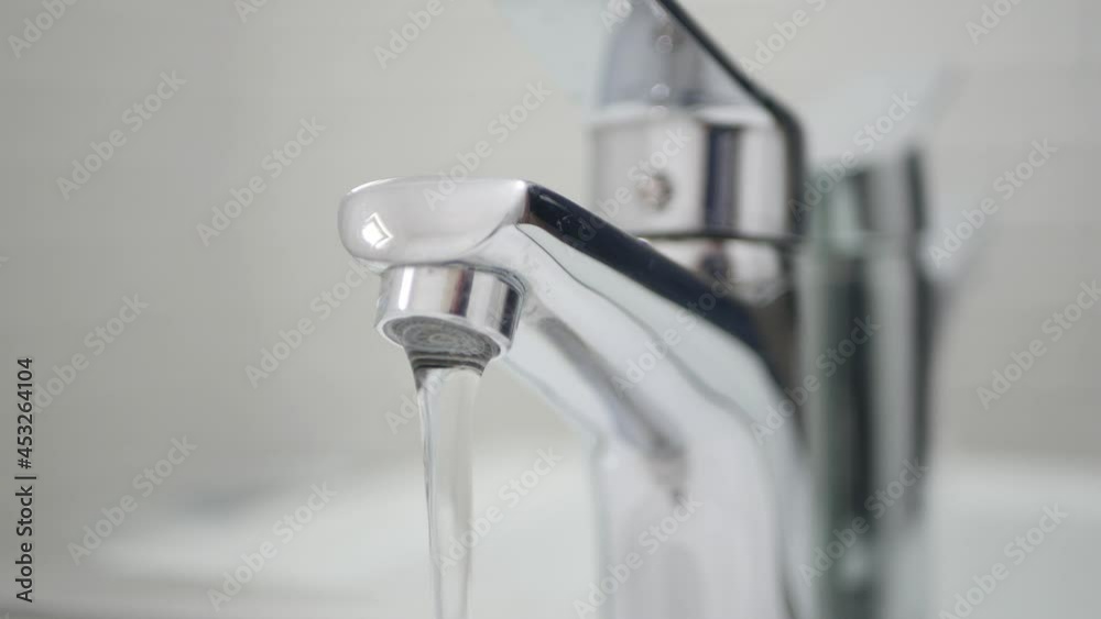 Medical Person Wearing Protective Gloves in Hands Opening the Sink Tap in the Bathroom. Medical Person Wearing Protective Gloves in Hands Opening the Sink Tap in the Bathroom.
