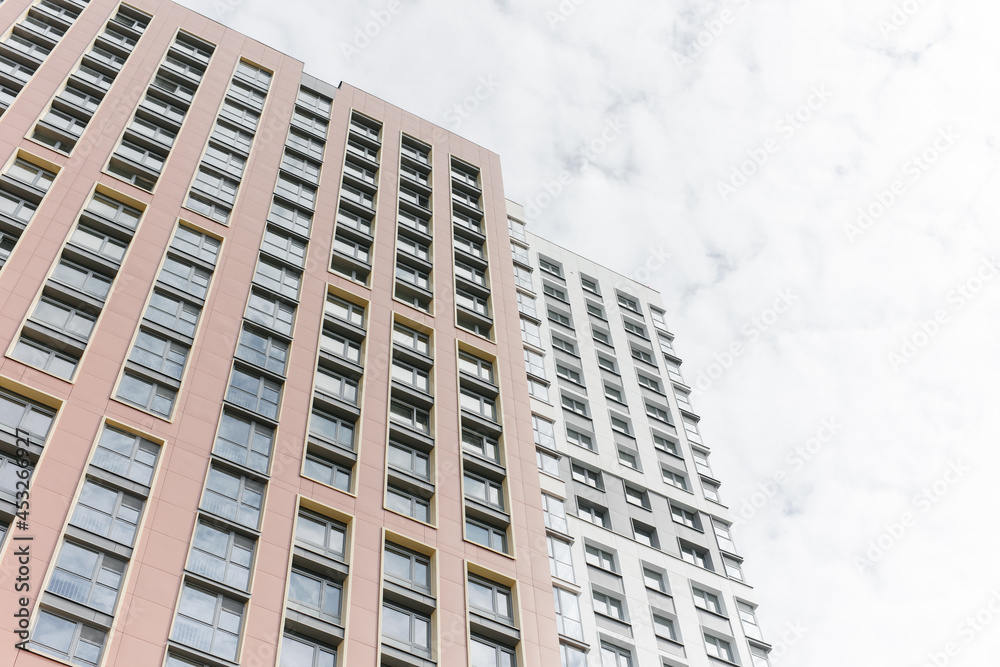 The facade of a high-rise residential building on a sunny summer day. a detailed picture of a building in the city. The blue sky is reflected in the windows. The facade of a high-rise residential building on a sunny summer day. a detailed picture of a building in the city. The blue sky is reflected in the windows.