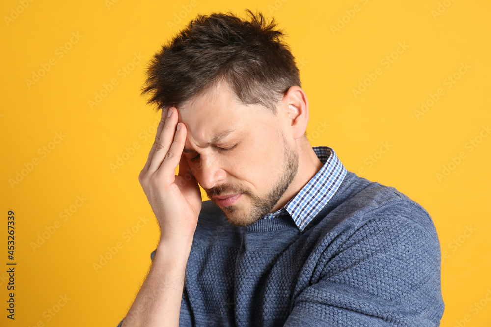 Man suffering from terrible migraine on yellow background Man suffering from terrible migraine on yellow background