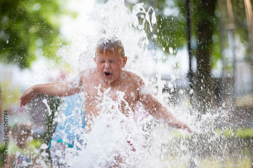 A little boy enjoys the cold waters of a fountain during the heat wave. Conceptual photography of hot weather, heat wave, global warming, summer season, climate change, enjoy life. © Светлана Лазаренко