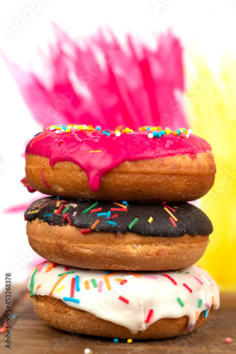 Creative sweet food. A stack of glazed colorful assorted donuts on a bright watercolor painted background.