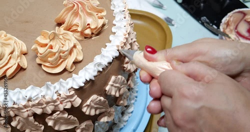 Confectioner woman is pouring cream on sponge cake using pastry bag, closeup view. Pastry chef is cooking homemade cake. cooking, baking and cooking, home cooking