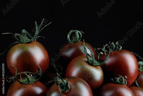 A few beautiful black tomatoes on a black background. Cumato tomatoes.