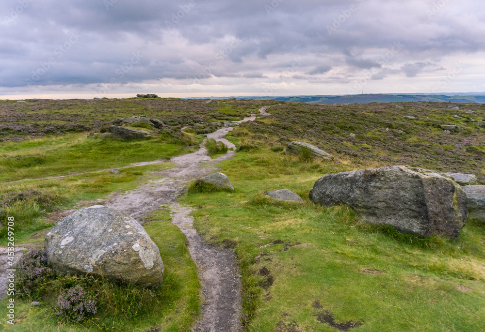 A Beautiful View of Stanage Edge With Rocks and a Tail Path with Heavy Clouds in Peak District, Sheffield, England A Beautiful View of Stanage Edge With Rocks and a Tail Path with Heavy Clouds in Peak District, Sheffield, England
