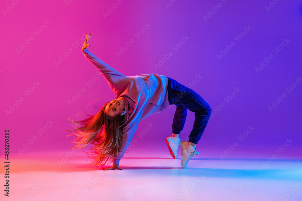 Beautiful active young girl dancing and showing hip-hop tricks isolated on  gradient pink purple neon studio background Stock Photo | Adobe Stock