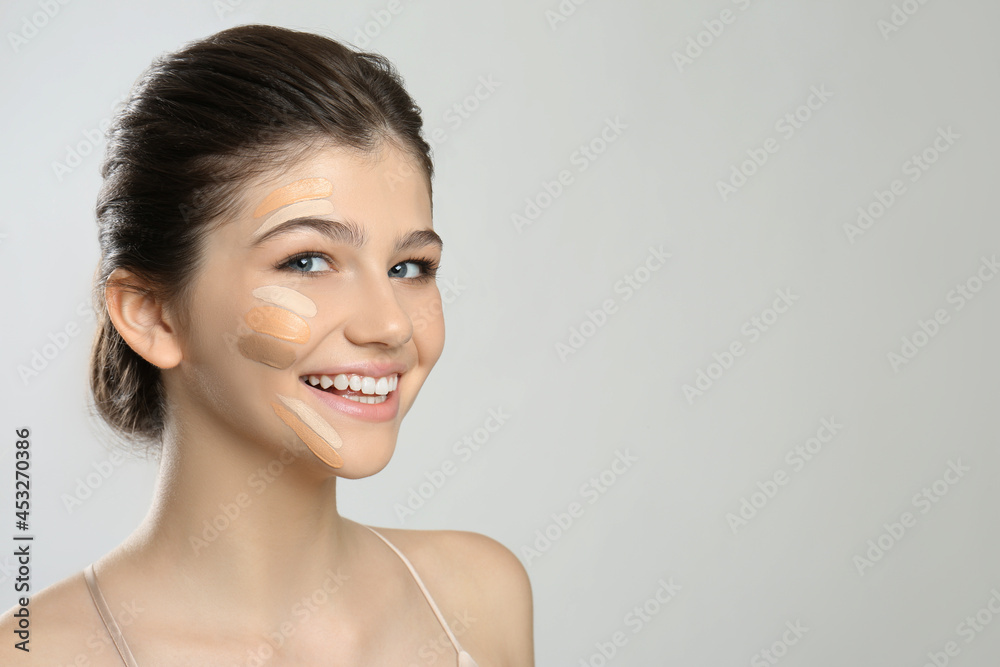 Beautiful girl on light grey background. Using concealers and foundation for face contouring