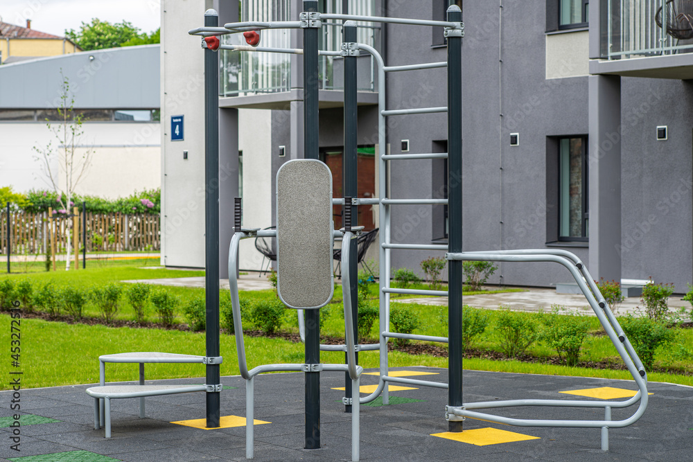Obraz premium Exercise equipment on playground in yard. Modern residential building.