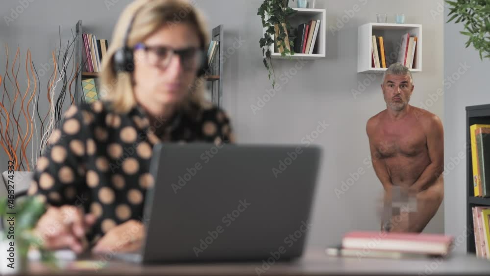 Comical funny situation,woman working remotely from home in conference video call,naked man appears in the background get busted from webcam,female works conferencing at the laptop,undressed husband