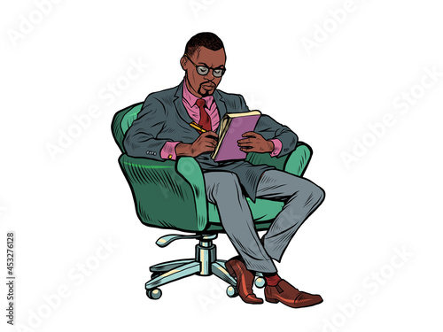 A black male psychotherapist is in a psychotherapy session, sitting in a chair and making notes in a notebook