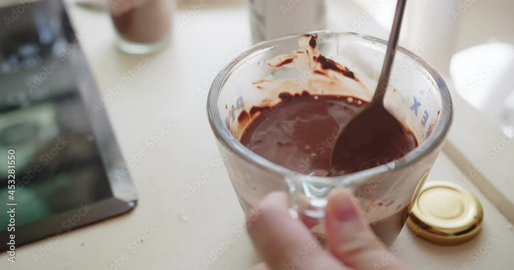 Close-up Person Hand Stirring mixes Blending chocolate milk in a glass, preparing homemade Iced cocoa milk Close-up Person Hand Stirring mixes Blending chocolate milk in a glass, preparing homemade Iced cocoa milk