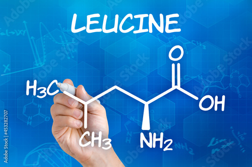 Hand with pen drawing the chemical formula of leucine photo