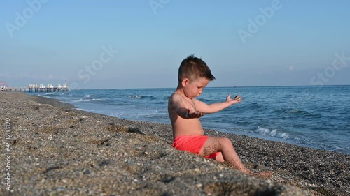 A child plays on the beach, against the background of the sea 