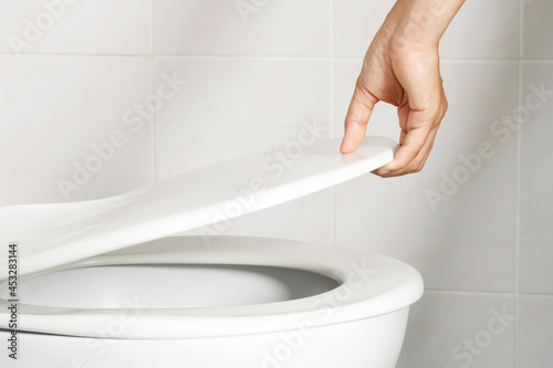 Obraz na plátně man's hand opening the toilet lid