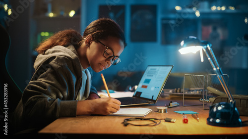 Young Teenage Multiethnic Schoolgirl is Studying Science Topic About Robotics at Home. Girl is Working on Homework for School. Young Female Reading Research Articles About Her Hobby. Education Concept