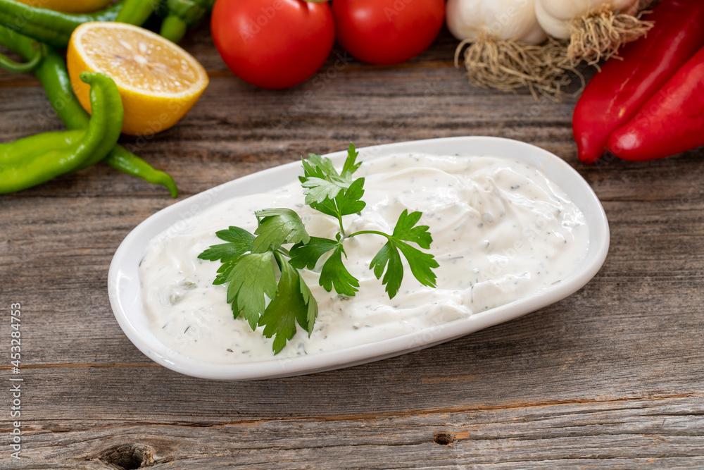 Haydari on a wooden background. Haydari is a type of yogurt made from certain herbs and spices, combined with garlic. Turkish cuisine. Close up, selective focus