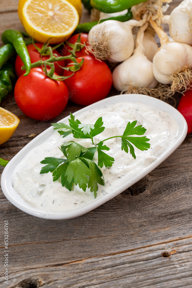 Haydari on a wooden background. Haydari is a type of yogurt made from certain herbs and spices, combined with garlic. Turkish cuisine. Close up, selective focus Haydari on a wooden background. Haydari is a type of yogurt made from certain herbs and spices, combined with garlic. Turkish cuisine. Close up, selective focus