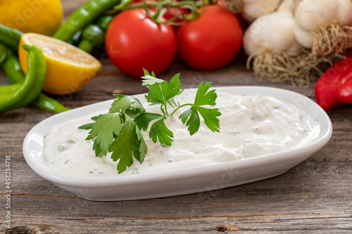 Haydari on a wooden background. Haydari is a type of yogurt made from certain herbs and spices, combined with garlic. Turkish cuisine. Close up, selective focus