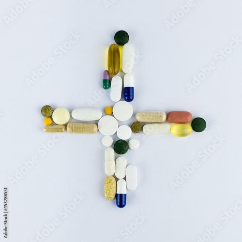 Pills arranged in a cross on a white background