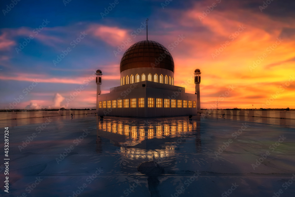 Central Mosque in Songkhla province in Thailand. This image taken in the upper part of mosque during sunset time with beautiful colorful sky. And saw a reflection from water on ground.