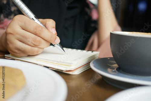 Close up of women hand writing on notepad.