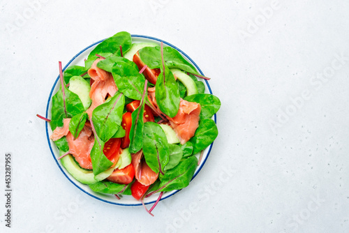 Salmon avocado salad, beet leaves, radicchio, tomatoes, lemon and olive oil dressing for keto and low card diet. Gray background, top view