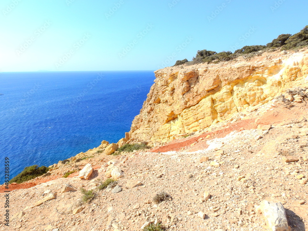 
rocky beach in the morning. steep cliffs in Koufonisi with the color of Clay and the sea of the Aegean August 2021
