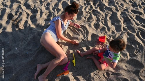 Mom plays with a child on the beach, top view 