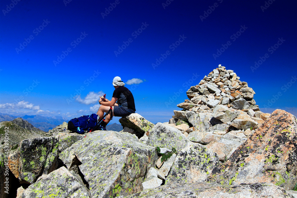 Un homme faisant une pause en haut d'un sommet pres d'un cairn