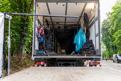 Open cargo box of filming movie set production equipment transport truck van vehicle with many electrical cables wire, rack and sockets on city streey outdoors. Cinema or television supply rental car photo