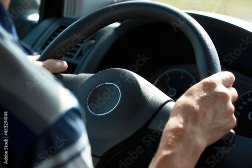 Man driving car, close-up. Driver hands holding steering wheel © Gecko Studio
