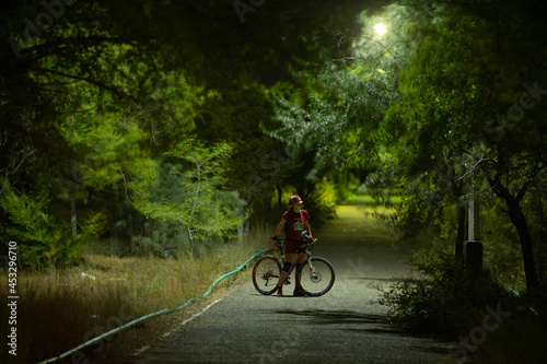 a girl with a bicycle in a night park