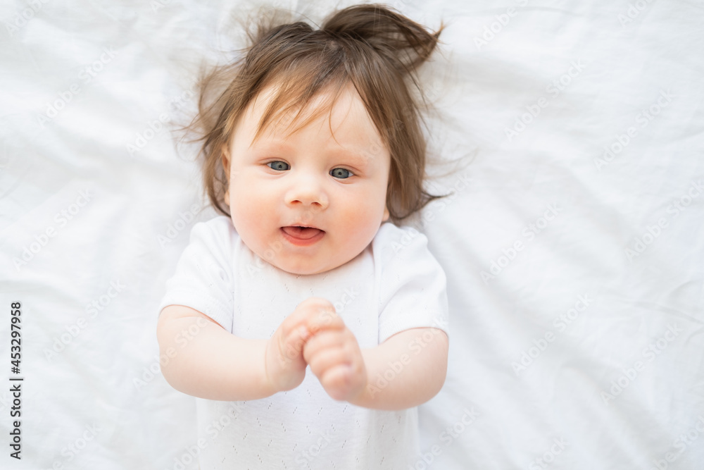 portrait of funny baby girl 6 month smiling and lying on a white bedding at home. portrait of funny baby girl 6 month smiling and lying on a white bedding at home.
