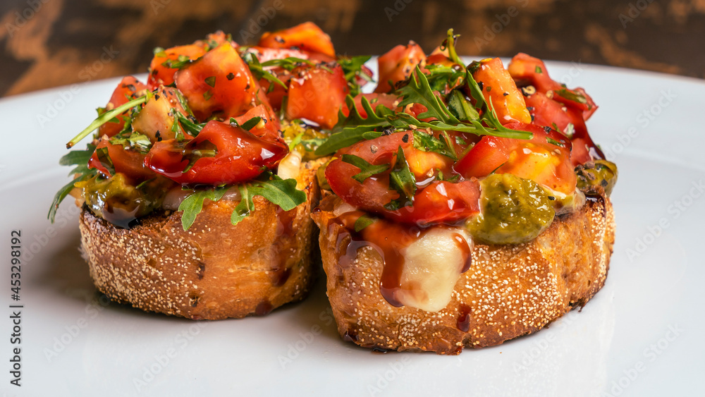 Close-up view of tomato and mozzarella bruschetta on white plate on red brick wall background. Healthy life concept.