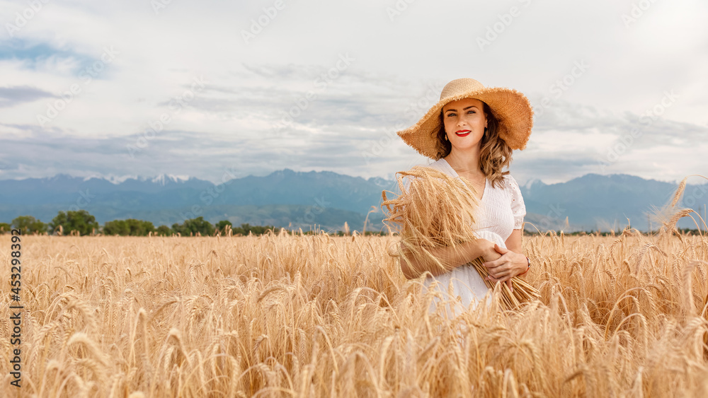 a young attractive woman in a white dress and a straw hat on a field of ripe cereals against a blue sky with clouds in autumn, the concept of harvesting, agribusiness and agriculture a young attractive woman in a white dress and a straw hat on a field of ripe cereals against a blue sky with clouds in autumn, the concept of harvesting, agribusiness and agriculture