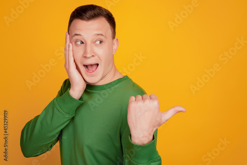 Portrait of funky crazy surprised guy direct finger blank space palm cheek sale reaction on yellow background photo