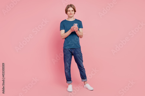 Full length photo of young guy happy positive smile use cellphone isolated over pink color background