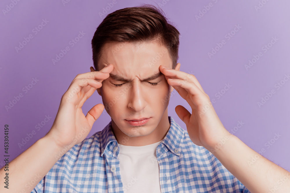 Portrait of tired unhealthy guy hands touch head suffer headache on purple background Portrait of tired unhealthy guy hands touch head suffer headache on purple background