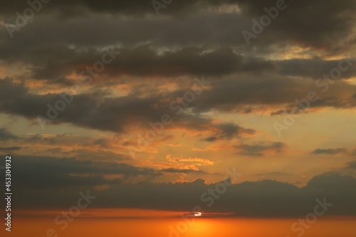 Orange dark dramatic sunset with black clouds in the sky, natural sunset background  © natalya2015
