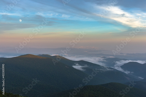 Fog in the mountains. The sun illuminates the top of the ridge. The fog floats on the mountains. Summer. © Александр Кузнецов