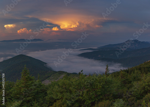 Sun-colored clouds. Fog floats over the mountains. 