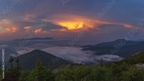 Sunset in the mountains. The clouds are illuminated by the sun. Fog in the valley. Summer.