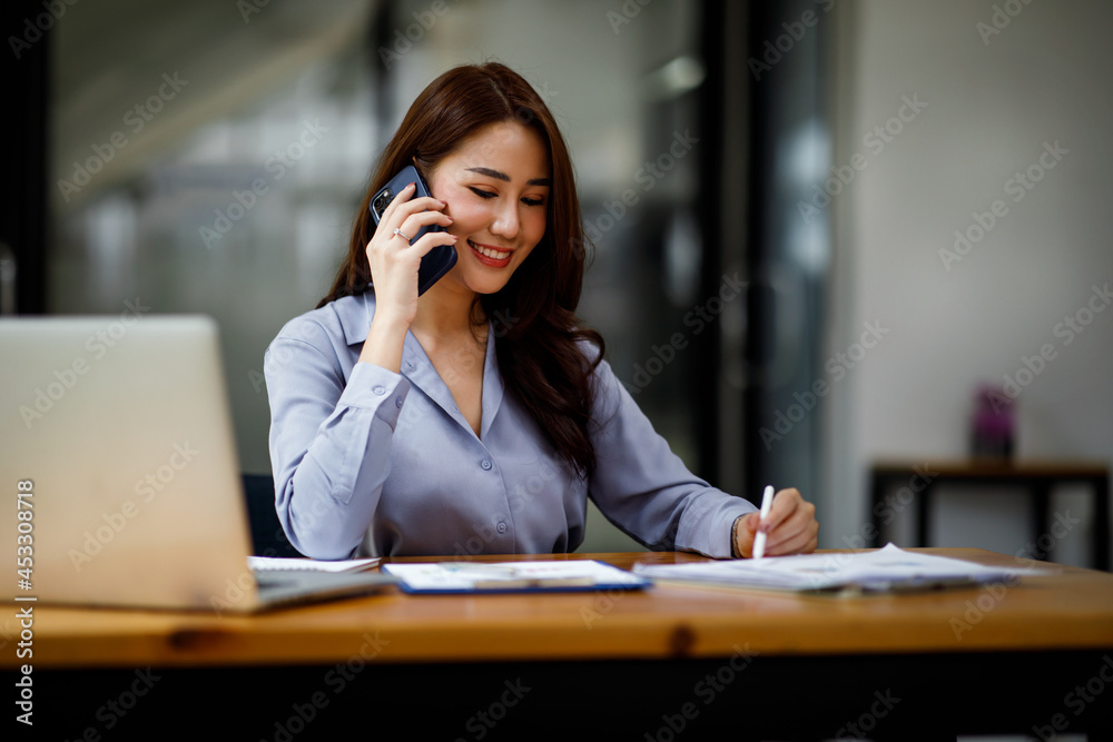 Professional young asian business woman using computer laptop and Talking On Phone Working On Laptop In Modern Office. - obrazy, fototapety, plakaty 
