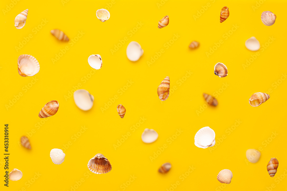 Levitation from above of sea shells of white and brown colors pattern on vibrant yellow background. Holidays travel and vacation concept with copy space Levitation from above of sea shells of white and brown colors pattern on vibrant yellow background. Holidays travel and vacation concept with copy space